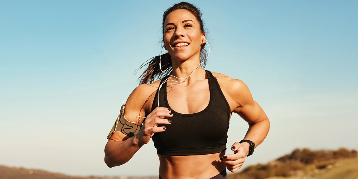 Fit woman running outdoors with headphones and an armband