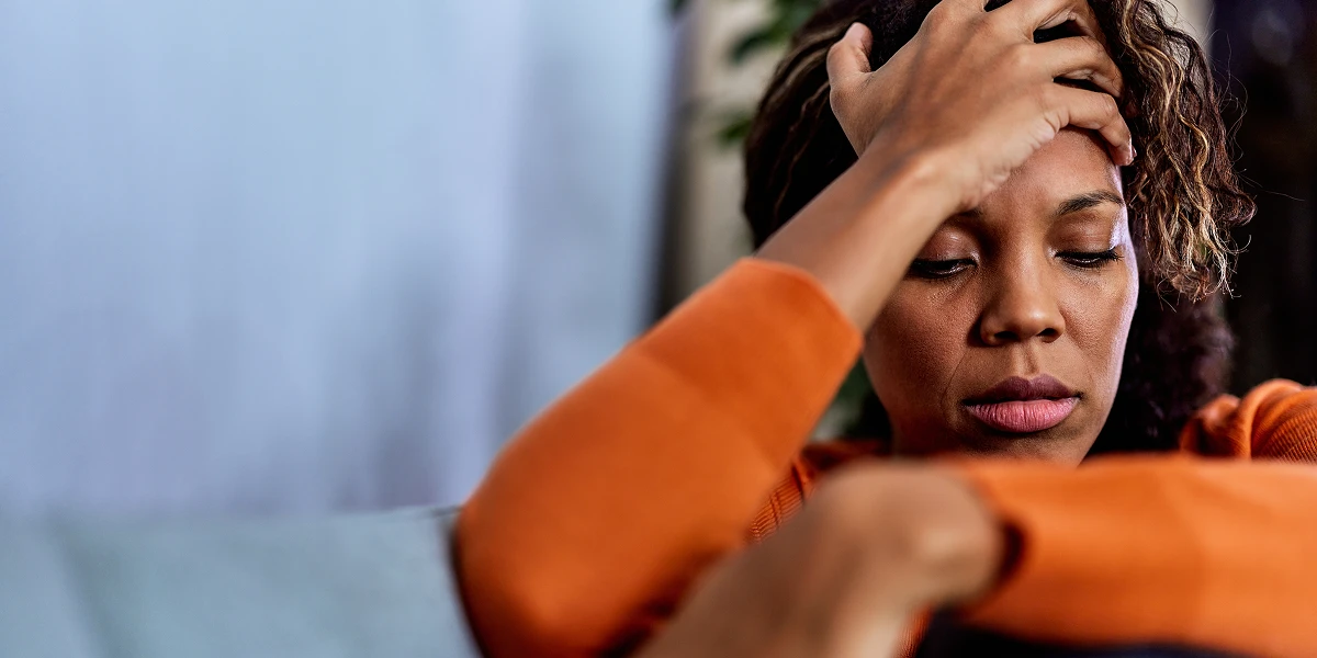Stressed woman sitting with her hand on her head, looking down