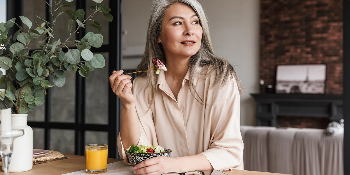 woman eating a fresh salad at home with orange juice on the table