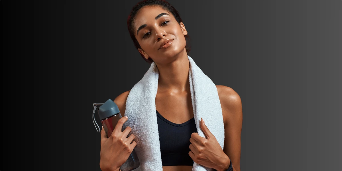 Woman after workout holding water bottle and towel, representing muscle recovery, fitness, and long-term health