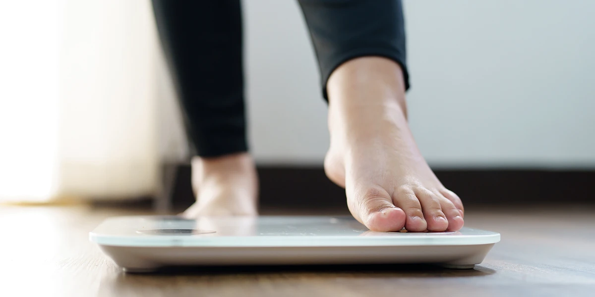 Foot stepping on scale illustrating why weight loss does not reflect true fat loss and body composition changes